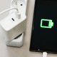 Chargeur secteur blanc branché sur une multiprise et relié par câble à un appareil dont l’écran affiche un symbole de batterie e Chargeur secteur blanc branché sur une multiprise et relié par câble à un appareil dont l’écran affiche un symbole de batterie e