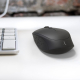 Souris sans fil noire en situation d’utilisation sur un bureau à côté d’un clavier, sans marquage publicitaire visible. Souris sans fil noire en situation d’utilisation sur un bureau à côté d’un clavier, sans marquage publicitaire visible.