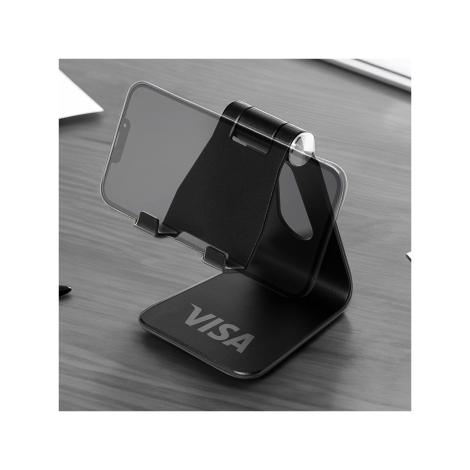 Support noir pliable pour smartphone personnalisé avec un logo, posé sur un bureau avec un téléphone installé horizontalement.