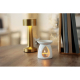 Brûleur de parfum en céramique blanche posé sur un meuble en bois, avec une bougie chauffe-plat allumée visible dans son ouvertu Brûleur de parfum en céramique blanche posé sur un meuble en bois, avec une bougie chauffe-plat allumée visible dans son ouvertu