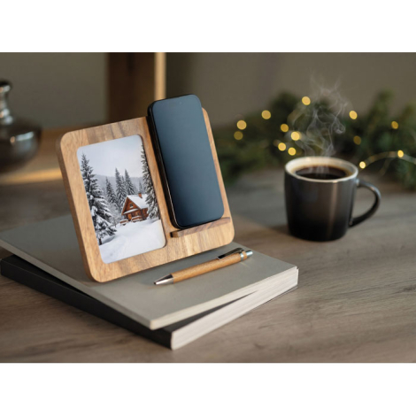 Support en bois avec photo et smartphone posé sur un carnet, accompagné d’un stylo et d’une tasse dans une mise en scène sur un 