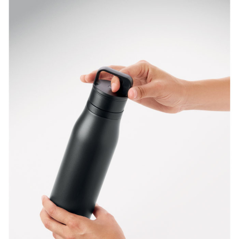 Bouteille isotherme noire tenue à deux mains, l’une saisissant la poignée intégrée au bouchon.