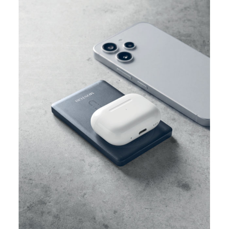 Batterie externe bleu foncé posée à plat avec un boîtier d’écouteurs sans fil placé sur sa zone de charge, à côté d’un smartphon