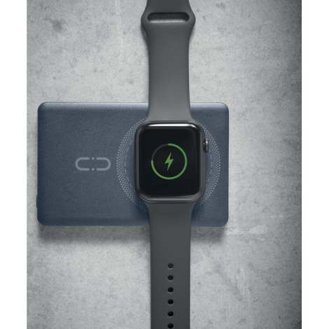 Montre connectée posée sur la zone de charge circulaire d’une batterie externe bleu foncé, avec symbole de charge affiché à l’éc