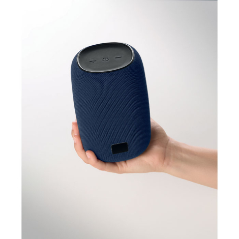 Haut-parleur bleu tenu dans une main, avec commandes visibles sur le dessus et petite plaque rectangulaire noire sur la partie b