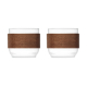Deux tasses à café transparentes en verre, présentées côte à côte et entourées d’une large poignée en bois foncé. Deux tasses à café transparentes en verre, présentées côte à côte et entourées d’une large poignée en bois foncé.