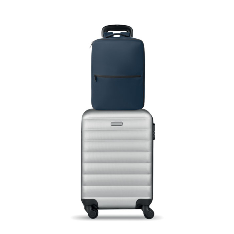 Sac à dos bleu marine installé sur la poignée télescopique d’une valise rigide grâce à sa sangle de bagage arrière.