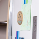 Magnet ovale en bois clair fixé sur la porte blanche d'un réfrigérateur, avec personnalisation noire et colorée composée de text Magnet ovale en bois clair fixé sur la porte blanche d'un réfrigérateur, avec personnalisation noire et colorée composée de text