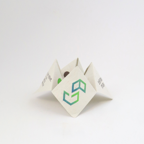 Cocotte en papier blanc personnalisée avec un logo géométrique vert et bleu sur sa face centrale, présentée ouverte sur fond bla
