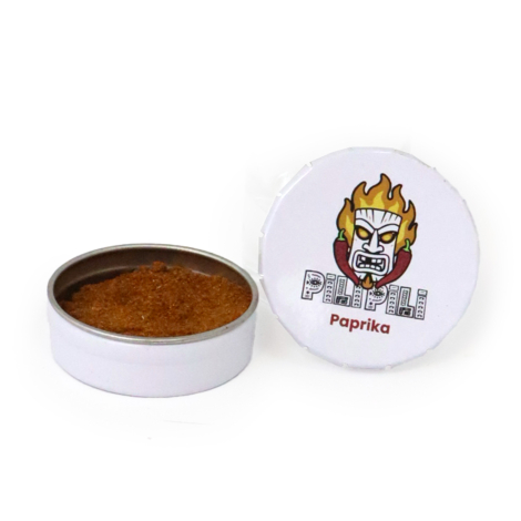 Petite boîte métallique ronde blanche ouverte contenant du paprika en poudre, accompagnée de son couvercle personnalisé avec le 