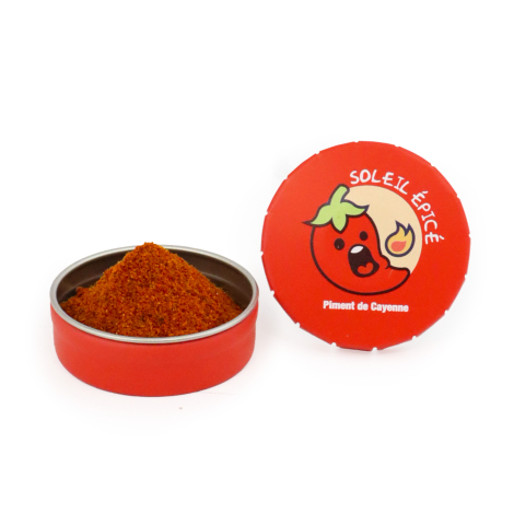 Boîte ronde rouge contenant du piment de Cayenne en poudre, présentée ouverte avec son couvercle personnalisé Soleil Épicé et un