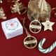 Gros plan sur un coffret de Noël personnalisé et trois suspensions en bois gravé, deux boules ajourées et une étoile, entourés d Gros plan sur un coffret de Noël personnalisé et trois suspensions en bois gravé, deux boules ajourées et une étoile, entourés d