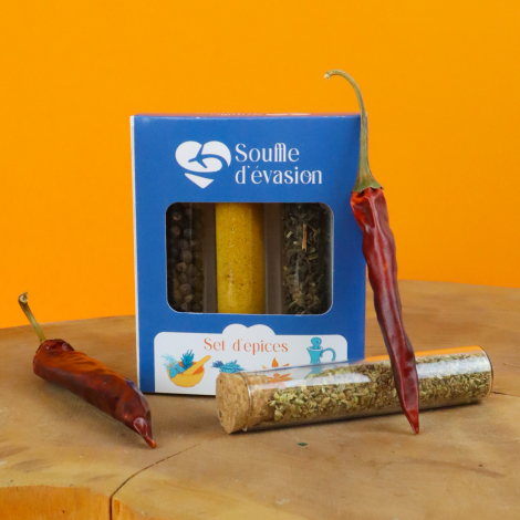 Coffret d'épices bleu personnalisé « Souffle d'évasion », présenté sur une surface en bois devant un fond orange. Fenêtre laissa