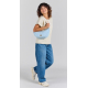 Femme portant à l'épaule le sac lune Inès bleu azur en forme de demi-lune, avec bandoulière écrue réglable et étiquette personna Femme portant à l'épaule le sac lune Inès bleu azur en forme de demi-lune, avec bandoulière écrue réglable et étiquette personna