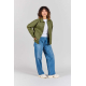 Femme portant la veste Camille vert olive ouverte sur un t-shirt blanc, avec fermeture boutonnée et deux poches plaquées sur le Femme portant la veste Camille vert olive ouverte sur un t-shirt blanc, avec fermeture boutonnée et deux poches plaquées sur le