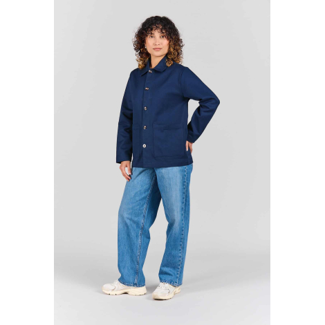 Femme portant la veste de travail Camille bleu marine, fermée par cinq boutons, avec col chemise, manches longues et deux grande