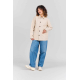Femme portant la veste de travail Camille écrue entièrement boutonnée, avec col chemise, manches longues, coupe droite et deux g Femme portant la veste de travail Camille écrue entièrement boutonnée, avec col chemise, manches longues, coupe droite et deux g