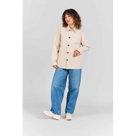 Femme portant la veste de travail Camille écrue entièrement boutonnée, avec col chemise, manches longues, coupe droite et deux g