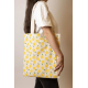 Cabas Nina écru à motifs citrons jaunes et feuilles vertes, porté à l'épaule par une femme, avec longues anses écrues et étiquet