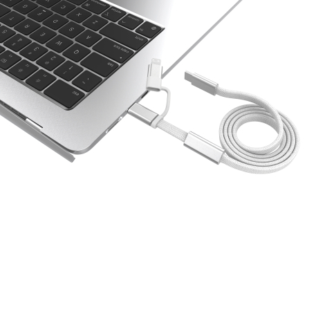 Câble de recharge blanc à gaine tressée, partiellement enroulé près d'un ordinateur portable argenté. Gros plan sur les connecte