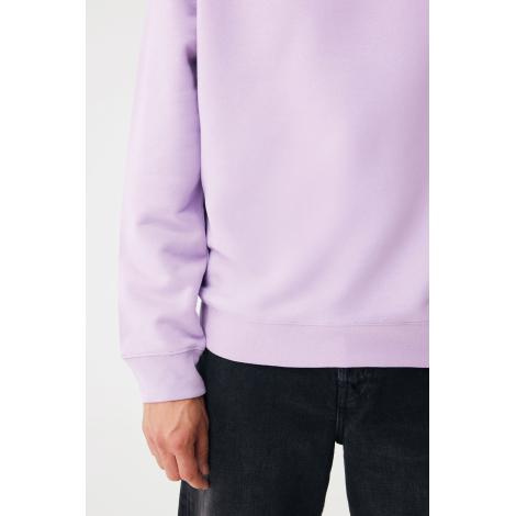 Gros plan sur le bas d'un sweat lilas clair porté avec un jean noir. Le tissu lisse, la bande côtelée à la taille et le poignet 
