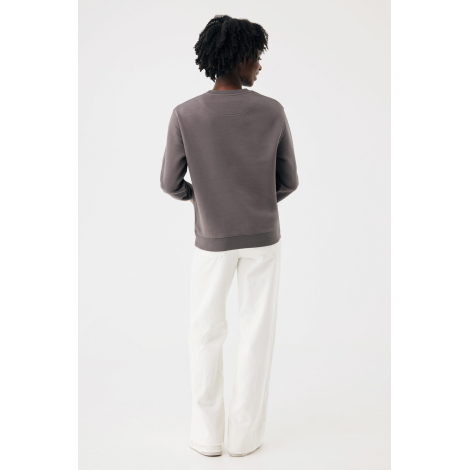 Femme photographiée de dos, portant un sweat gris taupe à col rond et manches longues, associé à un pantalon blanc ample. Une co