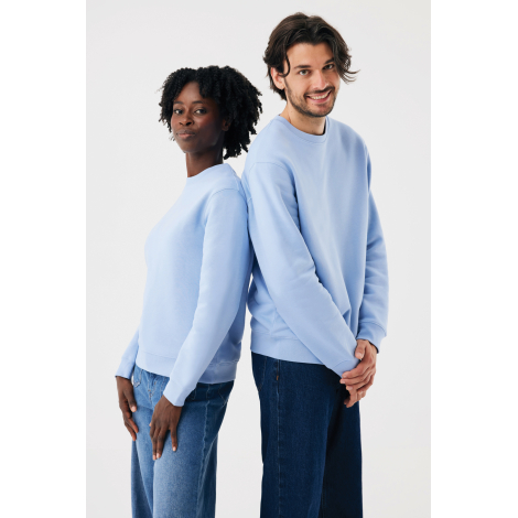 Une femme et un homme posent dos à dos, vêtus de sweats bleu ciel à col rond et manches longues, associés à des jeans bleus. Le 