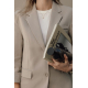 Femme vêtue d'un blazer beige et d'un haut blanc, tenant contre elle une bouteille isotherme noire mate avec manchon en silicone Femme vêtue d'un blazer beige et d'un haut blanc, tenant contre elle une bouteille isotherme noire mate avec manchon en silicone