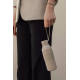 Gros plan sur une femme en blazer beige et pantalon noir, portant une bouteille isotherme beige clair par sa dragonne souple. Le Gros plan sur une femme en blazer beige et pantalon noir, portant une bouteille isotherme beige clair par sa dragonne souple. Le