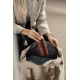 Femme blonde en blazer beige, plaçant une bouteille isotherme bordeaux mate dans un grand sac beige ouvert. La bouteille possède Femme blonde en blazer beige, plaçant une bouteille isotherme bordeaux mate dans un grand sac beige ouvert. La bouteille possède