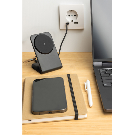 Support noir branché sur prise murale posé sur un bureau avec ordinateur portable