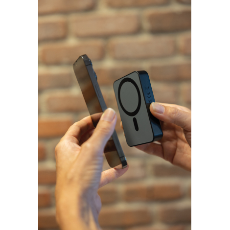 Batterie noire tenue en main face à un smartphone, vue de profil