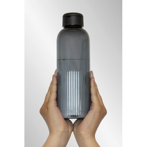 Bouteille grise translucide tenue à deux mains montrant la texture verticale