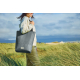 Sac cabas gris porté à l’épaule en extérieur de profil, aucun marquage visible