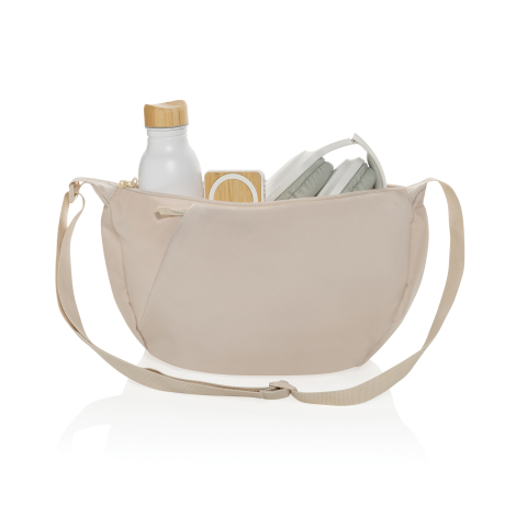 Sac bandoulière beige ouvert avec gourde, casque audio et enceinte visibles.