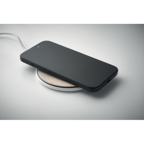 Chargeur sans fil rond en liège et tissu beige avec smartphone posé dessus, sans marquage.