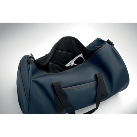 Sac de sport bleu marine ouvert vu du dessus, poche intérieure visible.