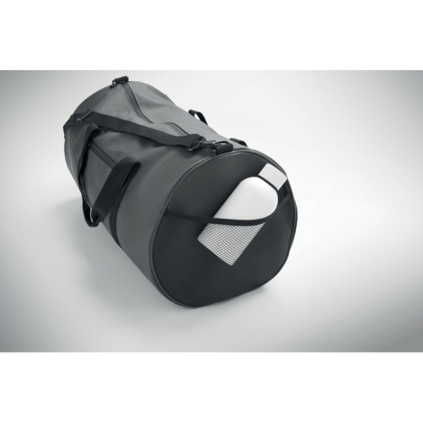 Sac de sport gris foncé vu de côté avec poche filet contenant une gourde blanche.