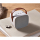 Enceinte sans fil blanche 5 W posée sur un carnet beige, boutons de commande visibles sur le dessus.