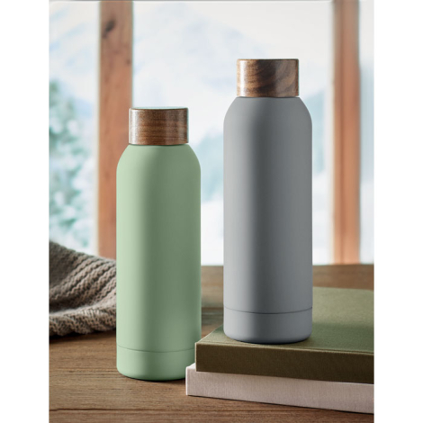 Deux bouteilles (vert clair et grise) posées sur une table en intérieur.