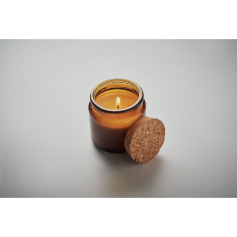 Bougie ambre en cire végétale dans pot en verre teinté, allumée, couvercle en liège à côté.