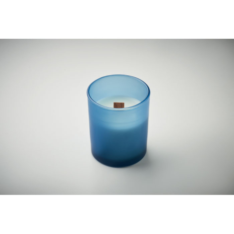 Bougie blanche en pot de verre bleu dépoli avec mèche en bois, allumée.