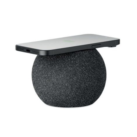 Enceinte sans fil ronde noire avec smartphone posé sur le dessus en charge.
