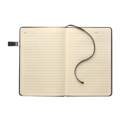 Carnet A5 ouvert à plat, pages lignées avec ruban marque-page, clé USB latérale déployée.