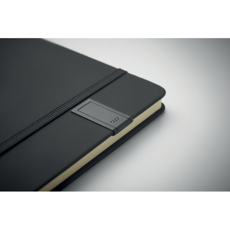 Gros plan sur l’angle inférieur d’un carnet A5 noir montrant le support latéral pour clé USB.