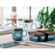 Mug en verre strié bleu présenté sur une table avec d’autres articles assortis, marquage visible sur le couvercle et la face ava