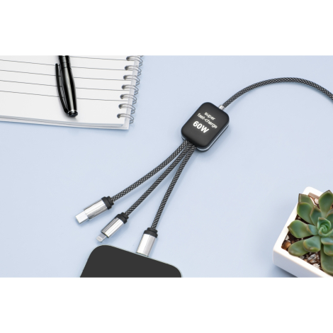 Câble noir posé sur une surface claire avec carnet et plante, trois embouts visibles, marquage sur le module.