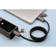 Câble noir branché à un ordinateur portable et à une batterie externe grise, enroulé sur une surface claire ; marquage visible s