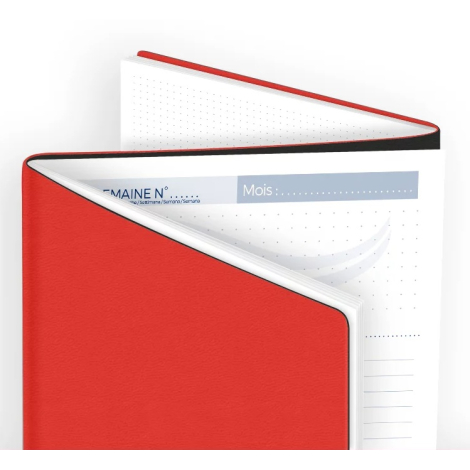 Gros plan d’un agenda rouge entrouvert montrant la première page intérieure avec zone de saisie mois et numéro de semaine.