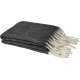 Couverture recyclée gris foncé pliée avec franges blanches visibles aux extrémités.